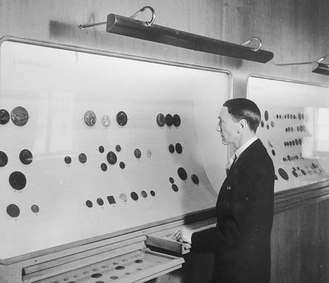 Black and white photo of person standing in an exhibition with coins