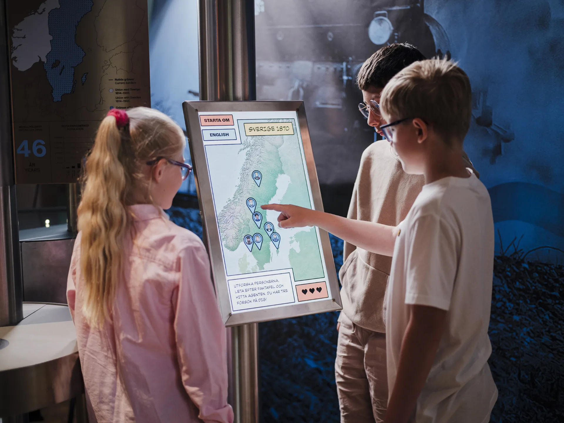 Tre barn trycker på en pekskärm i en utställning.