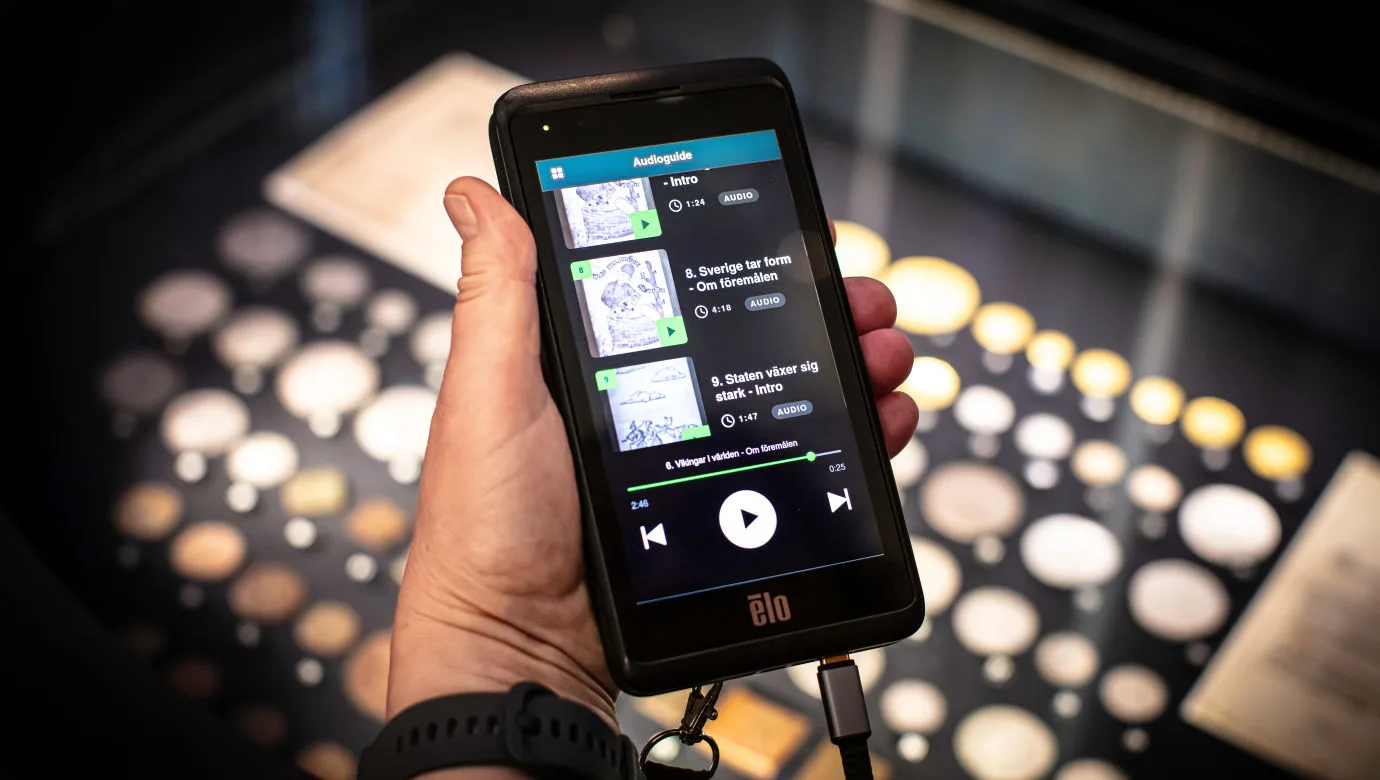 Image of the museums's audioguide being held in the hand of a visitor