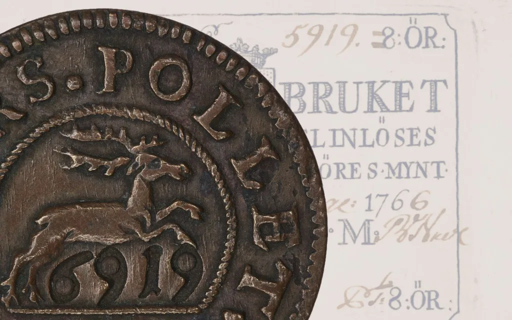 Ett kopparfärgat mynt med ett tryckt papper som bakgrund.