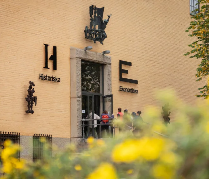 Ingången till Ekonomiska museet. Byggnadens fasad och ett träd utan löv i förgrunden.