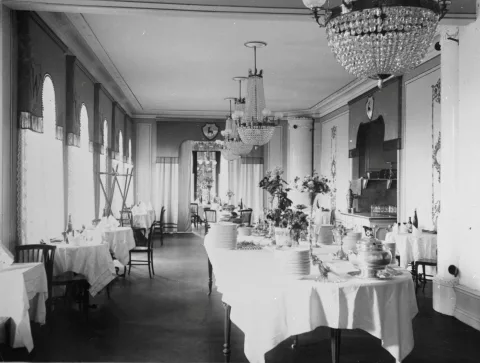 Matsal med kristallkronor i taket och bord med vita dukar. 