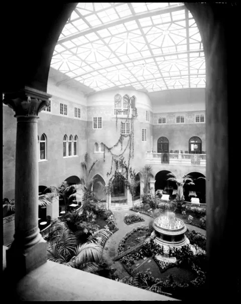 Ett stort rum med glastak, pelare och växter. I mitten finns en fontän. 