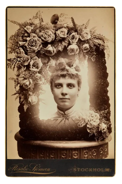 Ett foto på en ung kvinna inuti en ram av rosor och växter. I fotografiets nedre kant står det: Rosalie Sjöman Stockholm
