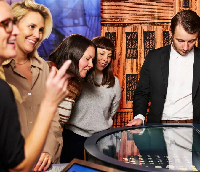 fem besökare som står vid en monter i museets lokaler