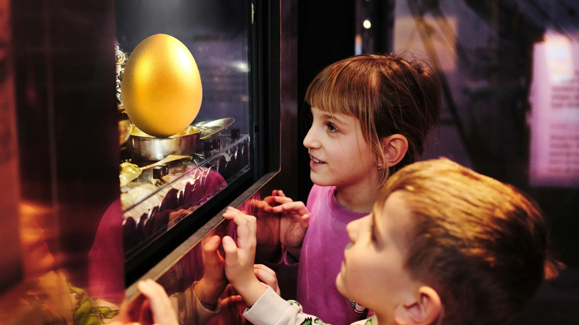 two young visitors looking at a golden egg inside a display case